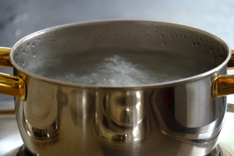 Boiling water in a steel bowl with golden handles