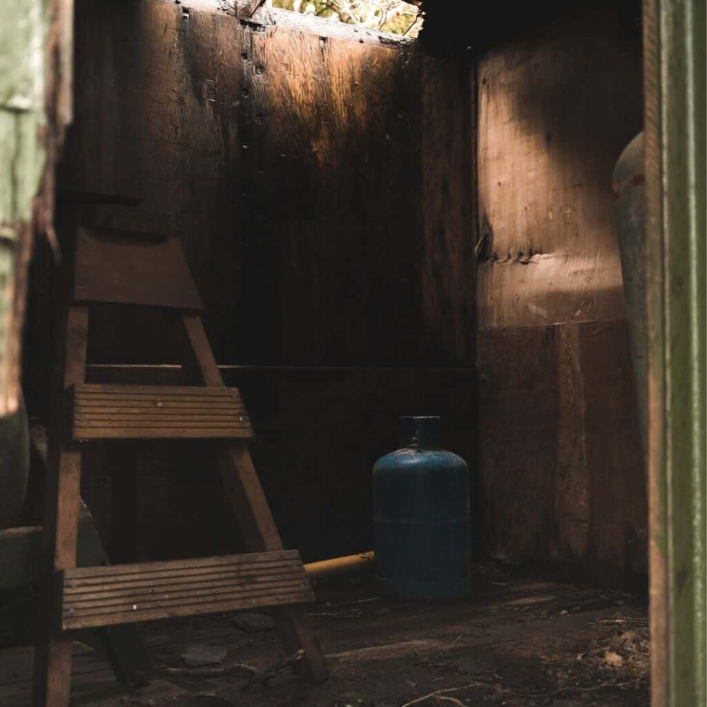 A blue colored phased out refrigerant cylinder at the corner of an old wooden storeroom
